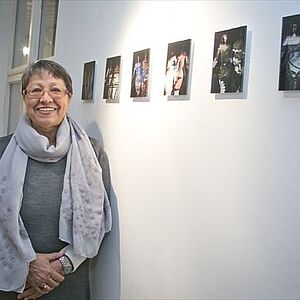Monika Maria Weiß steht vor ihren Werken, 6 Fotografien - 20 mal 30 cm, aufgehängt in Kopfhöhe der Künstlerin