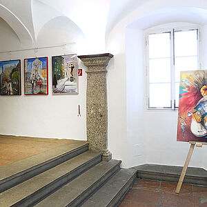 Ansicht eines Teiles der Rathaus Säulenhalle mit Bildern an den Wänden und zwei Bilder auf je einem Stativ.