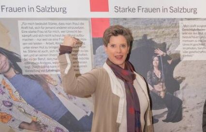 Eine Frau steht vor einem Plakat um die Staerke der Frauen zu promoten.