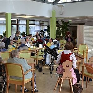 Senioren und Seniorinnen sitzen zusammen mit Musik
