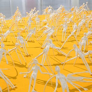 Ansammlung kleiner Figuren auf gelben Grund als Teilausschnitt der Installation