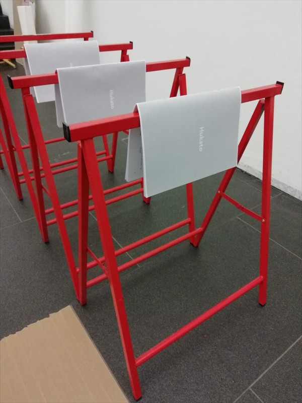 Ausstellungsansicht von roten Alu-Böcken mit aufliegenden aufgeklappten Heften
