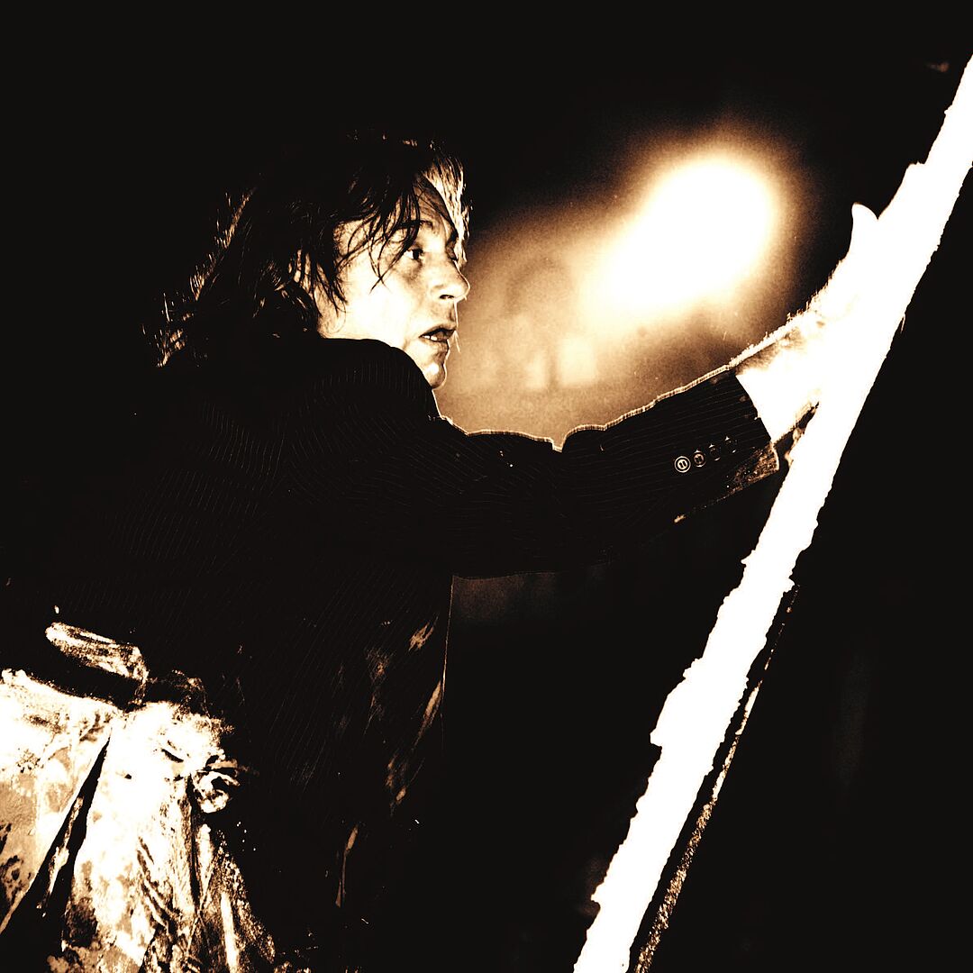 Schwarz-weiß Fotografie eines Mannes im Profil in Dunkelheit mit einer hellen Leuchtquelle im Hintergrund, das Gesicht ist jedoch für den Betrachter trotzdem sichtbar