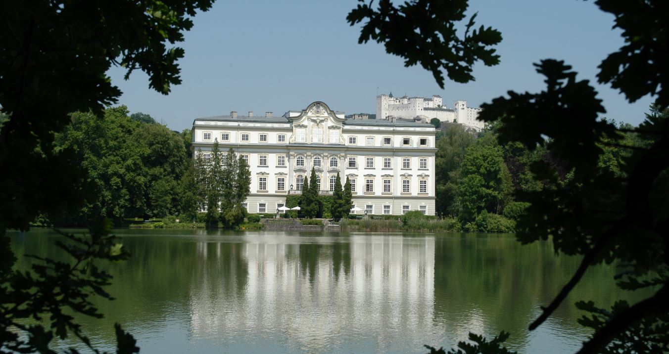 Das Schloss Leopoldskron hinter einem Teich und mit Blick auf die Festung