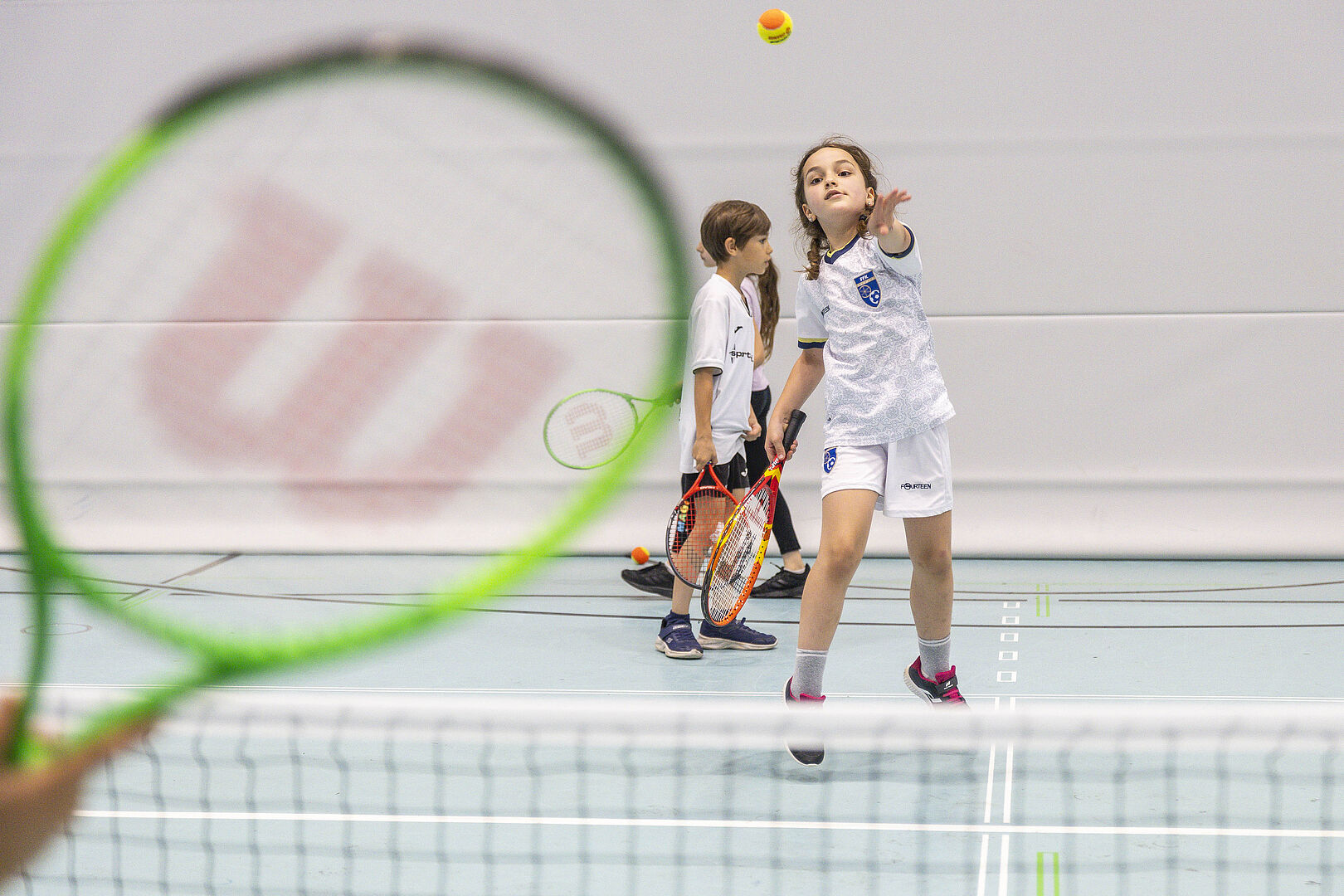 Tennis für Kinder und Jugendliche zum Reinschnuppern. Zei Kinder spielen in einer Halle Tennis.